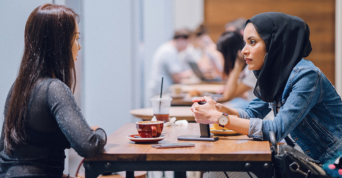 Two friends talk over coffee.