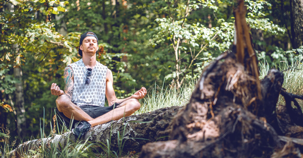 A man meditates in the forest.