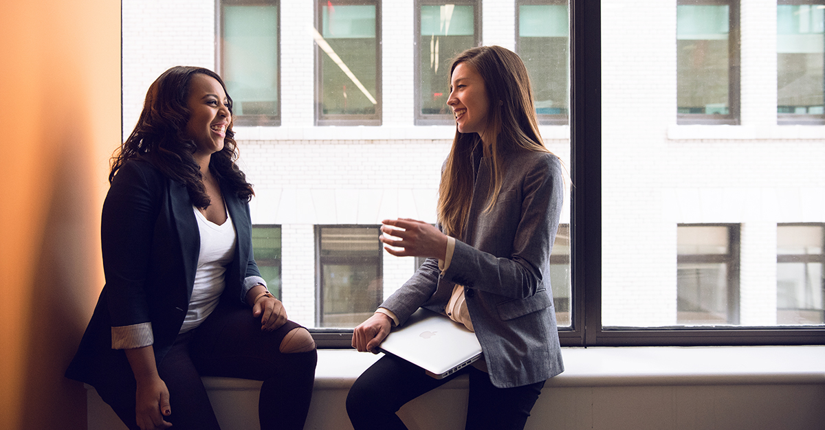 Two colleagues chat next to a window.